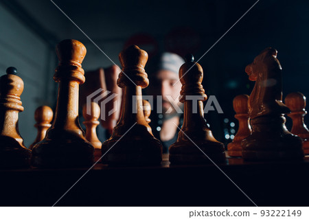 Young adult handsome man playing chess in dark with side lit. 93222149