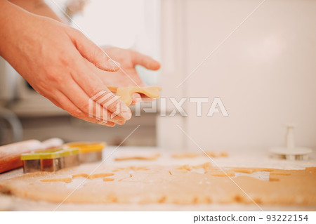 Woman hands form molds cutters ginger dough and makes delicious christmas ginger cookies. Cooking and decorating christmas dessert. Woman hands form molds cutters ginger dough and makes delicious christmas ginger cookies. Cooking and decorating christmas dessert. 93222154