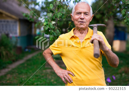 Senior man standing in yard of his country house Senior man standing in yard of his country house 93222315