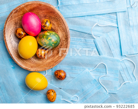 COVID-19 Flat lay. Colored Easter eggs on a background of blue medical masks COVID-19 Flat lay. Colored Easter eggs on a background of blue medical masks 93222685