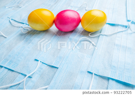 COVID-19 Flat lay. Colored Easter eggs on a background of blue medical masks COVID-19 Flat lay. Colored Easter eggs on a background of blue medical masks 93222705