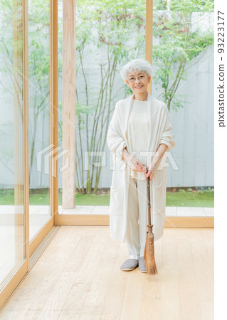 Senior woman cleaning the room with a broom Senior woman cleaning the room with a broom 93223177
