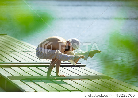 One young bearded man meditating yoga on river berth at sunrise, outdoors. Concept of mental health, relaxation, harmony with nature One young bearded man meditating yoga on river berth at sunrise, outdoors. Concept of mental health, relaxation, harmony with nature 93223709