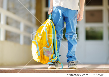Little student with a backpack on the steps of the stairs of school building. Close-up of child legs, hands and schoolbag of boy standing on staircase of schoolhouse.Back to school concept. Little student with a backpack on the steps of the stairs of school building. Close-up of child legs, hands and schoolbag of boy standing on staircase of schoolhouse.Back to school concept. 93225030