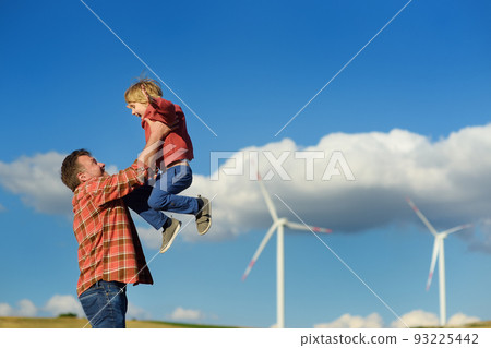 Eco activists man and child on background of power stations for renewable electric energy production. People and windmills. High wind turbines for generation electricity. Green energy 93225442