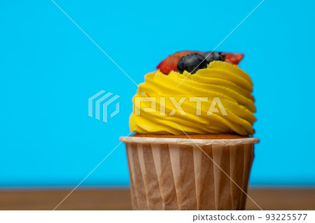 Cupcake with yellow sweet cream on a blue background 93225577