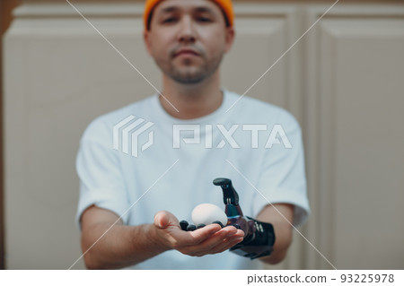 Young disabled man holding fragile chicken egg with artificial prosthetic hand in casual clothes Young disabled man holding fragile chicken egg with artificial prosthetic hand in casual clothes 93225978