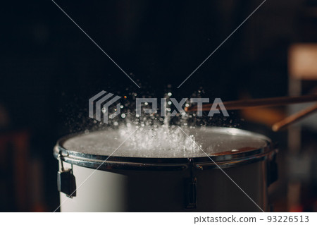 Close up drum sticks drumming hit beat rhythm on drum surface with splash water drops Close up drum sticks drumming hit beat rhythm on drum surface with splash water drops 93226513