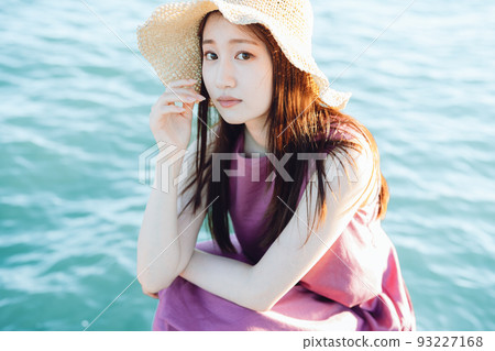 坐在海邊的草帽的年輕女人 坐在海邊的草帽的年輕女人 93227168