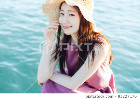 坐在海邊的草帽的年輕女人 坐在海邊的草帽的年輕女人 93227170