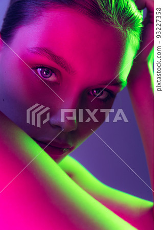 Portrait of young, beautiful and healthy girl with well-kept skin isolated on dark background in neon light. Art, fashion, style, facial expression Portrait of young, beautiful and healthy girl with well-kept skin isolated on dark background in neon light. Art, fashion, style, facial expression 93227358