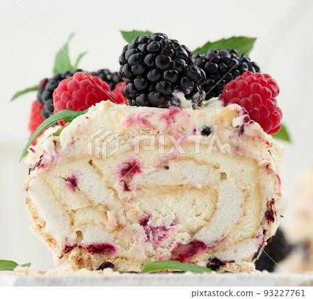 Baked meringue roll with cream and fresh fruits on a white wooden board, delicious dessert 93227761