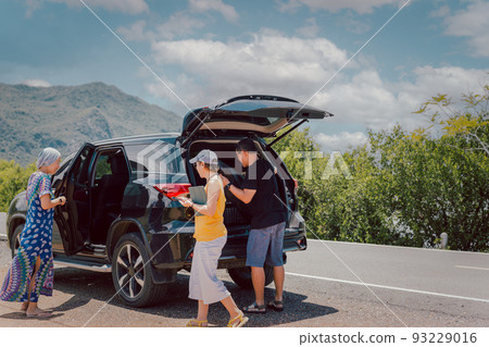Man with friends loading luggage in trunk of automobile, travelling on summer holiday. 93229016