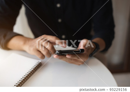 Male are using smartphone to work at the desk in the mornin Male are using smartphone to work at the desk in the mornin 93229156