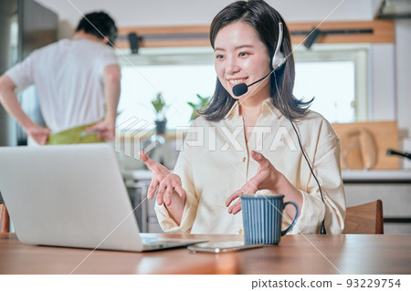 A woman who has a web conference by telework and a man who does housework 93229754