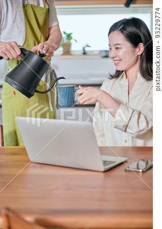 Husband serving coffee to his wife in the kitchen 93229774