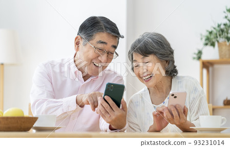 A smiling senior couple who operates a smartphone A smiling senior couple who operates a smartphone 93231014
