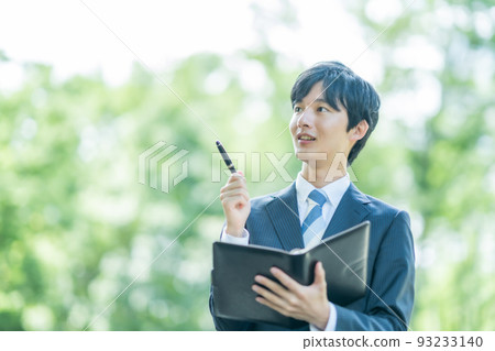 一個帶著智能手機四處走動的年輕商人 一個帶著智能手機四處走動的年輕商人 93233140