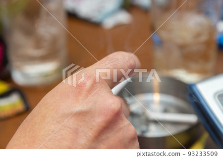 Hand of a man who smokes a cigarette with a snack Hand of a man who smokes a cigarette with a snack 93233509