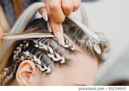 Hairstylist braided afro braids dreadlocks kanekalon pigtails hair of female client in barber salon. Hairstylist braided afro braids dreadlocks kanekalon pigtails hair of female client in barber salon. 93234643