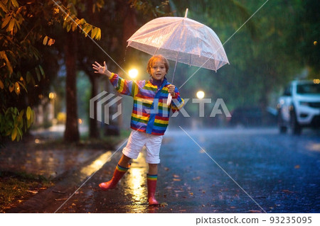 Child playing in autumn rain. Kid with umbrella. 93235095