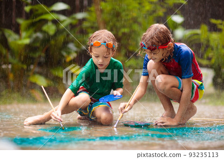 Kids playing in the rain. Chalk drawing fun. Kids playing in the rain. Chalk drawing fun. 93235113
