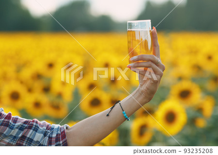 Woman farmer with sunflower oil at sunflowers field. Harvesting and farming concept 93235208