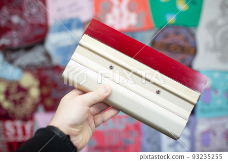 Serigraphy silk screen print process at clothes factory. Frame, squeegee and plastisol color paints. Serigraphy silk screen print process at clothes factory. Frame, squeegee and plastisol color paints. 93235255