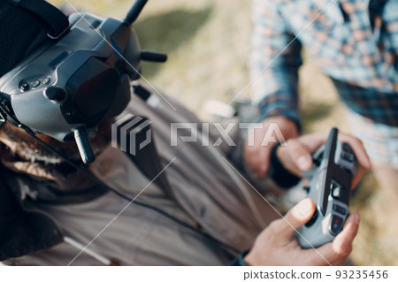 Man controlling fpv quadcopter drone for aerial photography and videography with goggles antenna remote controller pad Man controlling fpv quadcopter drone for aerial photography and videography with goggles antenna remote controller pad 93235456