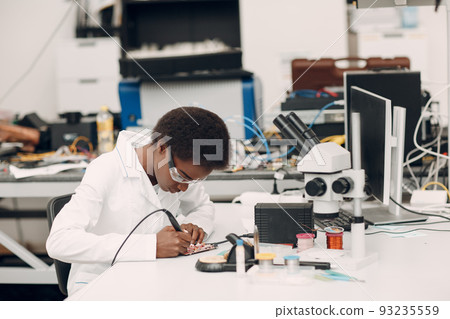 Scientist african american woman working in laboratory with soldering iron. Research and development of electronic devices by color black woman. 93235559