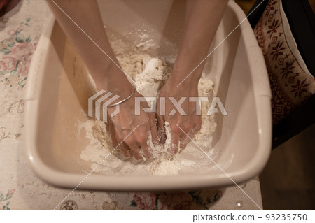 Female hands kneading dough in bowl on table close up. Winter holiday spirit. 93235750