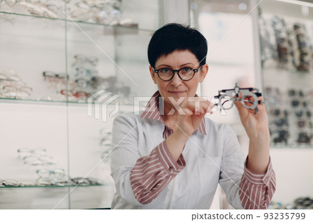 Happy Optician Choosing Eyeglasses, female optometrist with glasses. 93235799