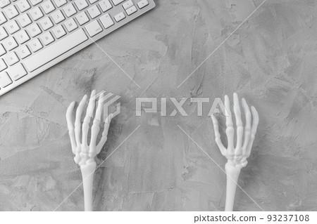 Halloween gray background with white skeleton hands and computer keyboard. Halloween holiday online shopping banner mockup. Top view, copy space Halloween gray background with white skeleton hands and computer keyboard. Halloween holiday online shopping banner mockup. Top view, copy space 93237108