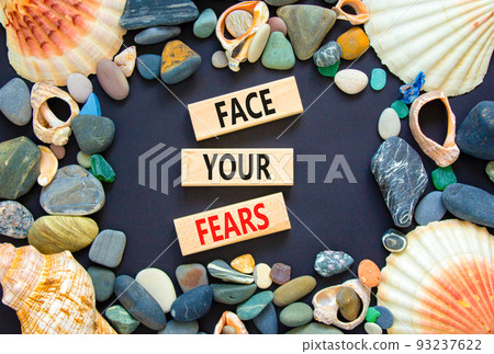Face your fears and support symbol. Concept words Face your fears on wooden blocks. Beautiful black background. Sea stones and sea shells. Business and Face your fears quote concept. Copy space. 93237622