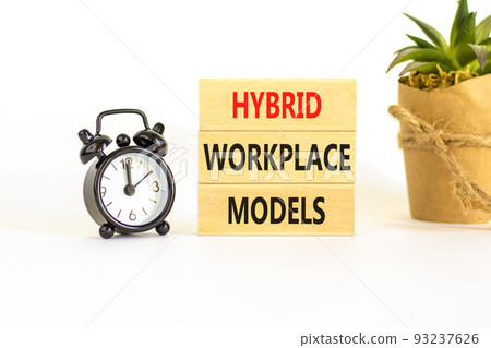 Hybrid workplace models symbol. Concept words Hybrid workplace models on wooden blocks. Black alarm clock. Beautiful white table white background. Business hybrid workplace models quote concept. Copy 93237626