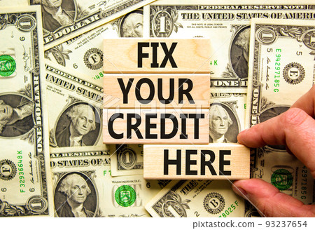Fix your credit here symbol. Concept words Fix your credit here on wooden blocks on a beautiful background from dollar bills. Businessman hand. Business, finacial and fix your credit here concept. 93237654