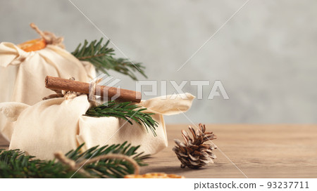 Zero waste christmas concept. Packed in natural fabric gifts and decorations from natural materials on gray table, copy space Zero waste christmas concept. Packed in natural fabric gifts and decorations from natural materials on gray table, copy space 93237711