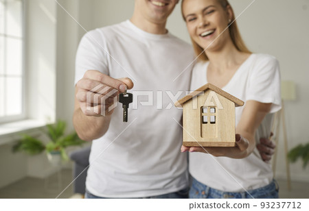 Happy young couple who have bought new house holding toy and keys to their new home 93237712