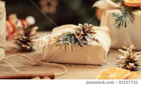 Zero waste christmas concept. Packed in natural fabric gifts and decorations from natural materials on a wooden table Zero waste christmas concept. Packed in natural fabric gifts and decorations from natural materials on a wooden table 93237720