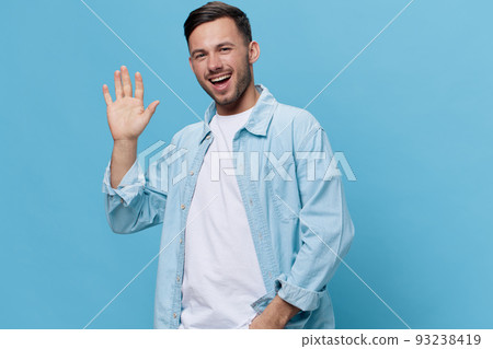 Smiling attractive tanned handsome man in casual basic t-shirt greeting show palm at camera posing isolated on blue studio background. Copy space Banner Mockup. People emotions Lifestyle concept 93238419
