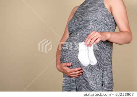Expecting a baby. Pregnant belly in profile with baby socks. Expecting a baby. Pregnant belly in profile with baby socks. 93238907