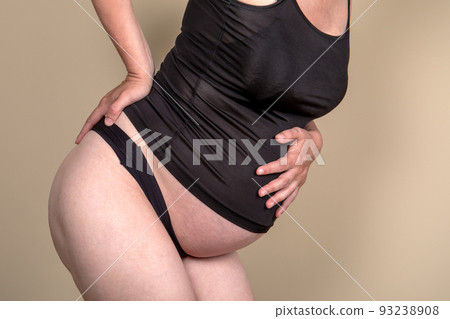 The pregnant woman holds her stomach and back. Back pain during pregnancy. The pregnant woman holds her stomach and back. Back pain during pregnancy. 93238908