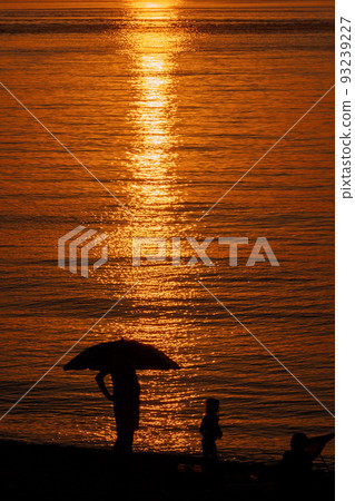 Man silhouette standing under umbrella at the sea beach. Beautiful view of orange sunset seascape. Summer resort vacation Man silhouette standing under umbrella at the sea beach. Beautiful view of orange sunset seascape. Summer resort vacation 93239227