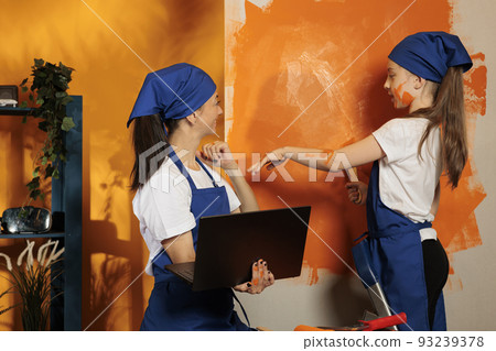 Small family finding painting inspiration on laptop, using online browser to search for home decor model and orange paint design. Adult and daughter looking at internet website to renovate. Small family finding painting inspiration on laptop, using online browser to search for home decor model and orange paint design. Adult and daughter looking at internet website to renovate. 93239378