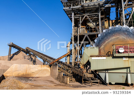 Close-up detail part of heavy metal construction of open pit gravel plant sand quarry big rusty rotor machine material excavating and crushing. Industrial machinery factory equipment steel background Close-up detail part of heavy metal construction of open pit gravel plant sand quarry big rusty rotor machine material excavating and crushing. Industrial machinery factory equipment steel background 93239384