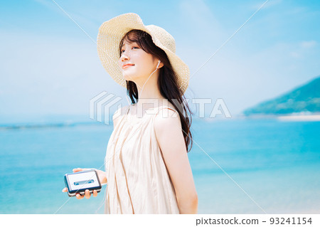 A woman listening to music by the beach 93241154