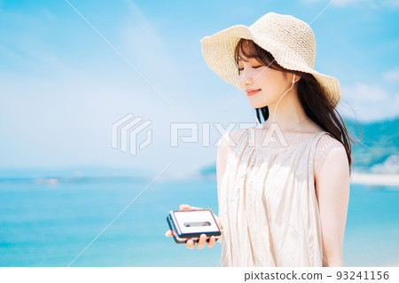A woman listening to music by the beach 93241156