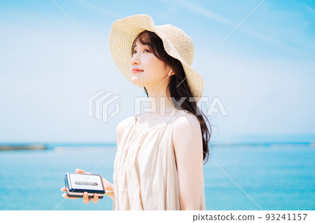 A woman listening to music by the beach 93241157