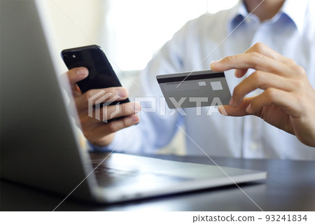 A man who pays with a personal computer, mobile phone, credit card paying by a credit card 93241834