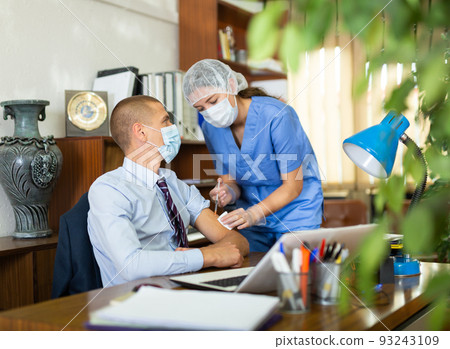 Young nurse in a protective mask, vaccinates a man Young nurse in a protective mask, vaccinates a man 93243109